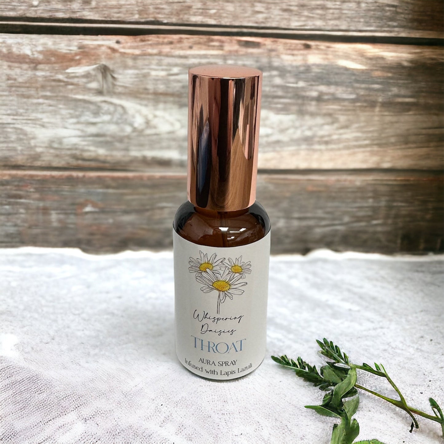 A 30ml glass bottle of 'Whisperinging Palms' Throat Aura Spray with a copper cap, labeled with a floral design and infused with Lapis Lazuli crystals.