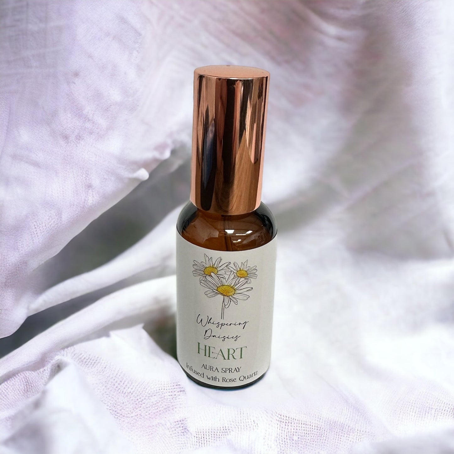 A 30ml glass bottle of 'Heart - Rose Quartz Crystal - Aura Spray' with a white label, gold-colored cap, and infused with rose quartz crystals.
